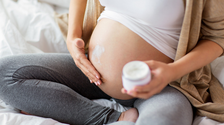 woman putting cream on belly 