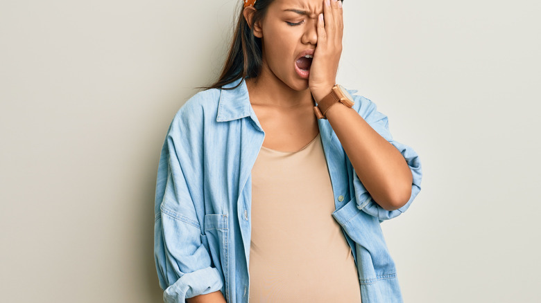 pregnant woman yawning and touching face