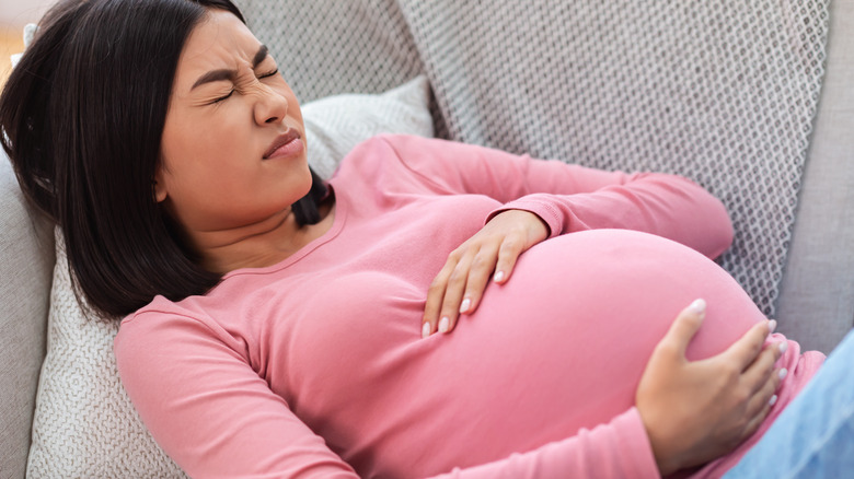 pregnant woman holding belly in pain 