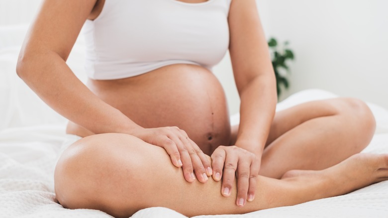 pregnant woman holding leg