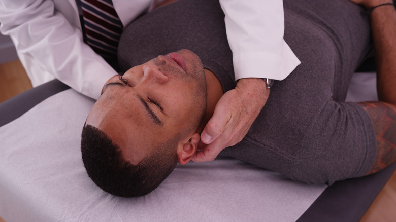 Doctor examining a patient's head and neck on exam table