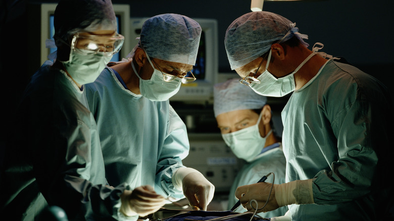 Four surgeons gathered around a patient
