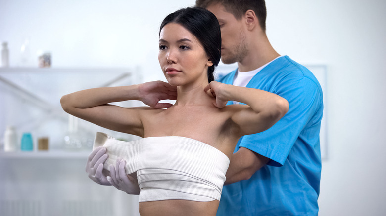 Doctor bandaging woman's chest