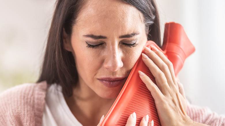 white woman using compress against jaw