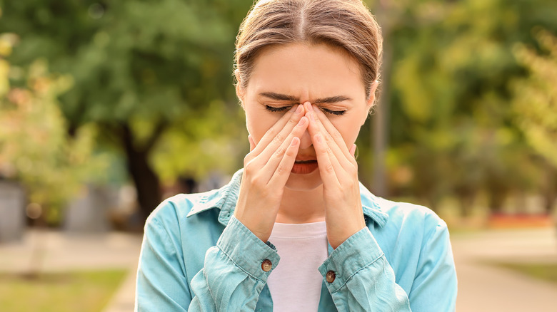 Young woman sneezing from pollen