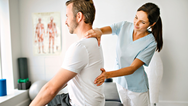 Female chiropractor adjusting man's spine