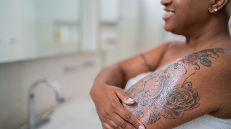 Smiling woman moisturizing tattoo