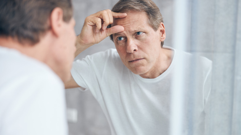Man looking at forehead in mirror