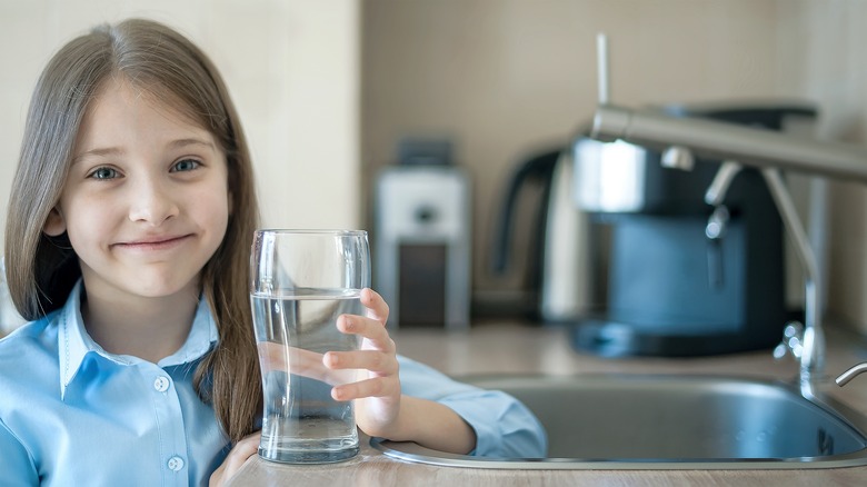 girl smiles with glass of tap water 