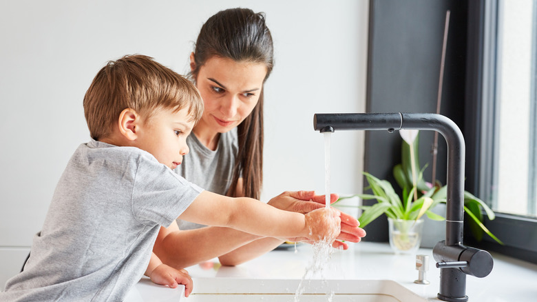 Mother teaching her child to wash him hands