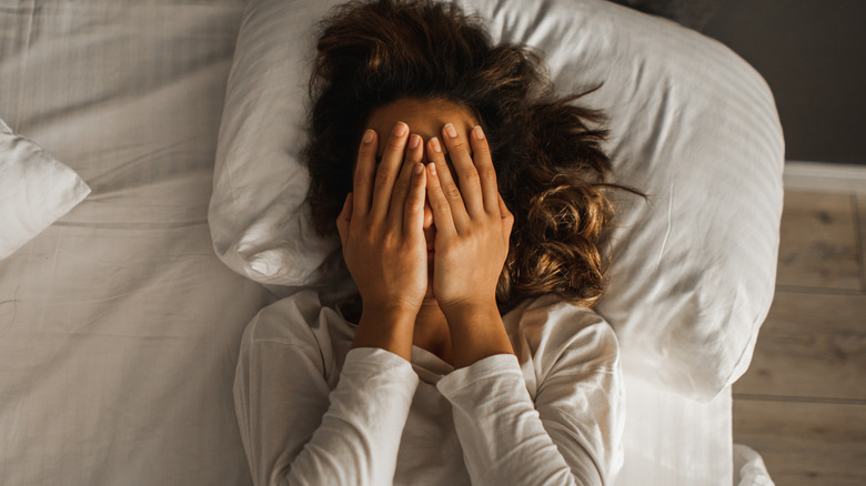 A woman with insomnia covering her face with her hands