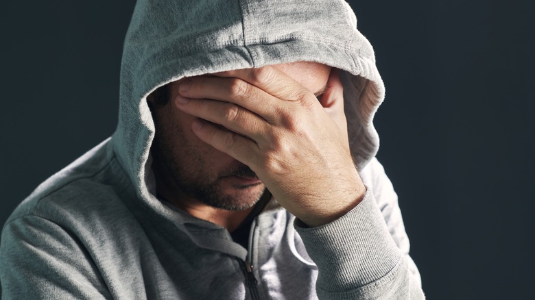 Man covering his face remembering traumatic event