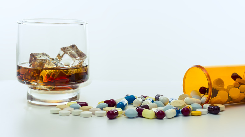 Whiskey glass next to a vial of pills