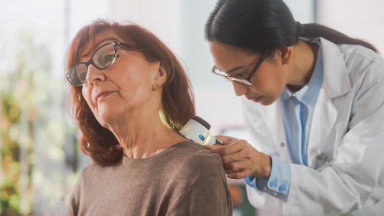 dermatologist checking woman for skin cancer