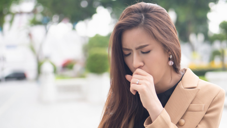 Woman coughing into hand