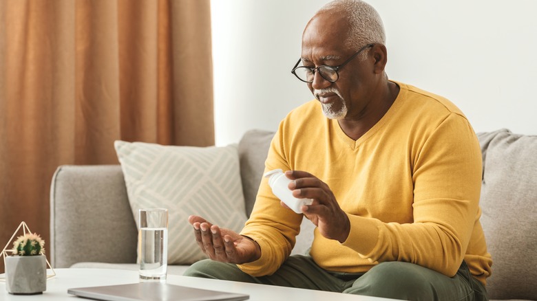 The old man looks at the supplements in his hand