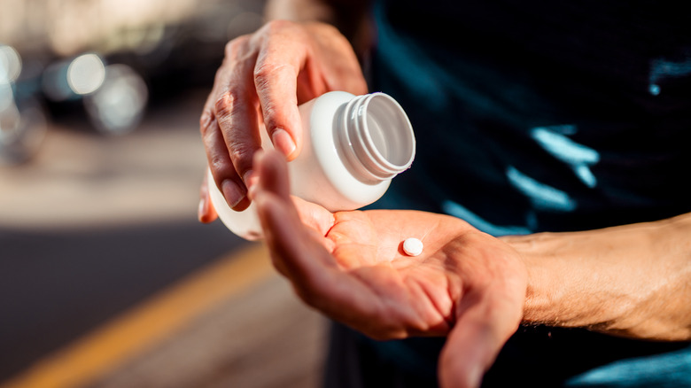 man's hands pouring out supplement tablets