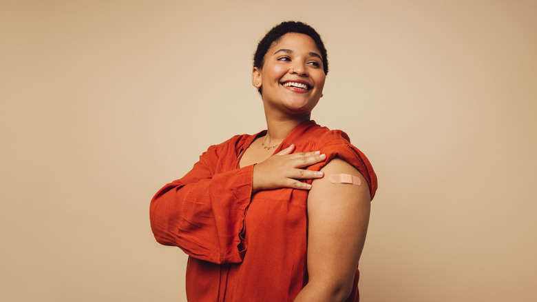 Female with bandage on her arm looking away and smiling