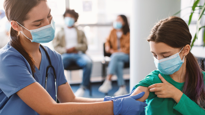 Nurse giving girl a bandaid on arm 