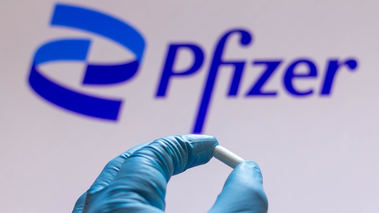 Gloved hand holding Pfizer pill