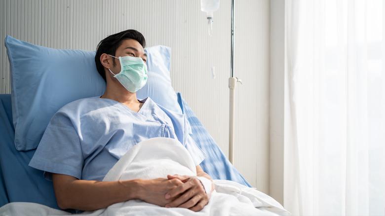 Patient lying on bed with face mask in recovery room in hospital ward