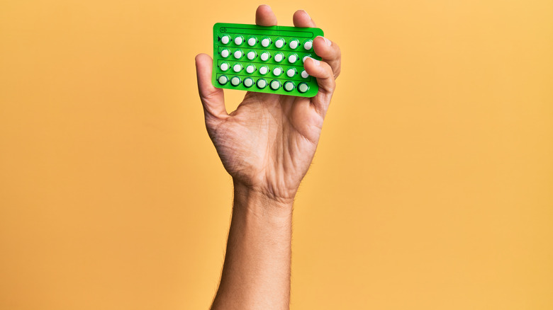 man holding blister pack of birth control pills