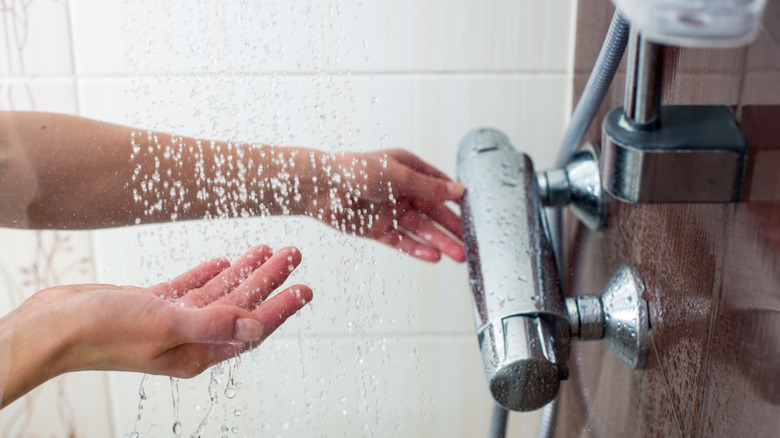 woman's hand adjusting shower temperature