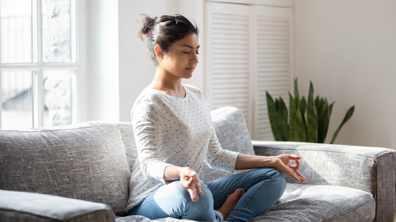Woman meditating on couch at home