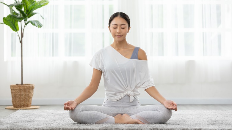 meditating girl sitting on white mat