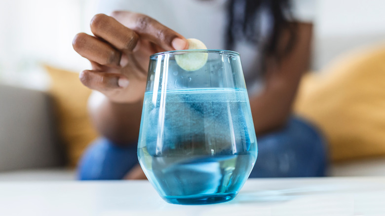 Woman dropping antacid into a glass