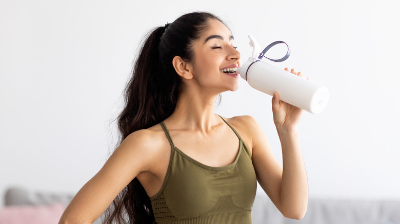 woman drinking water after workout