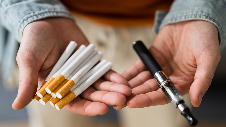 Hands holding cigarettes and vape