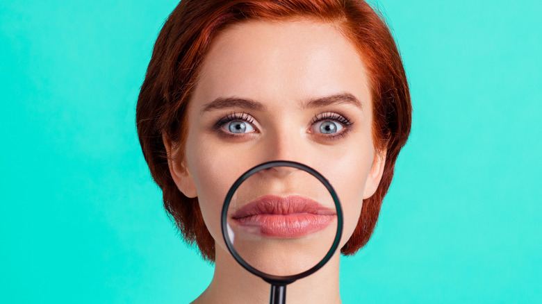 Problematic self-image represented by a woman holding a magnifying glass up to her lips