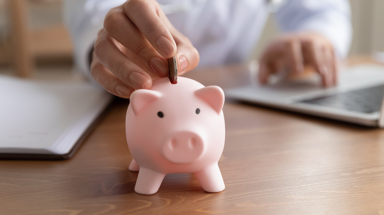 Doctor putting money in a piggy bank