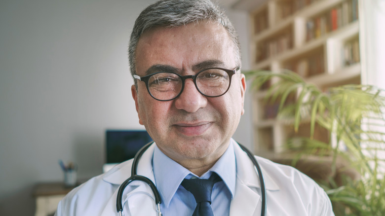 A white-haired surgeon smiling