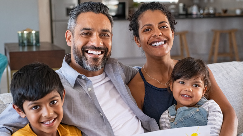 Smiling family seated on couch with mother, father, and two children