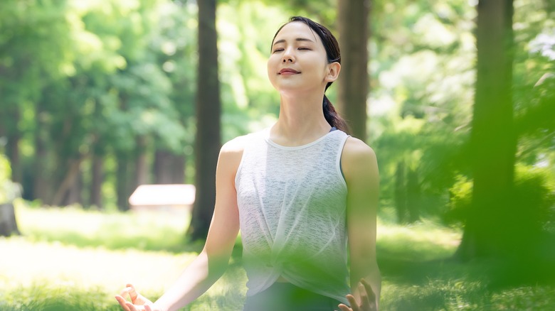 Asian woman meditating in the woods