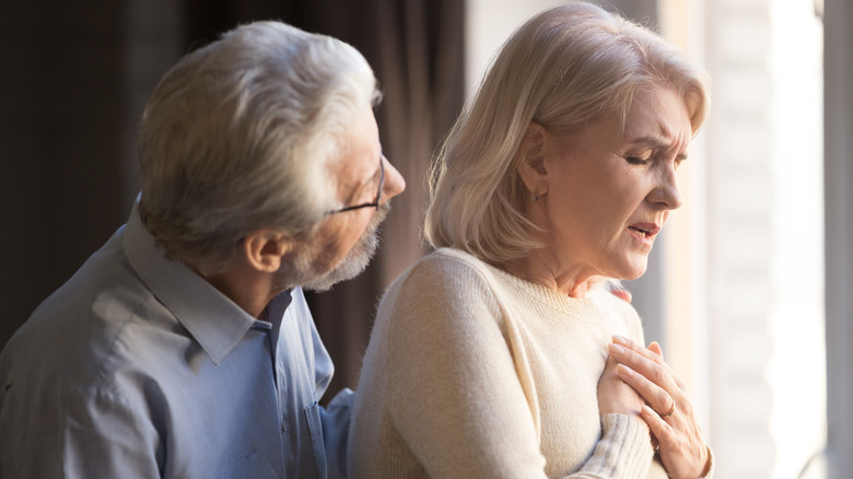 An elderly woman holds her heart