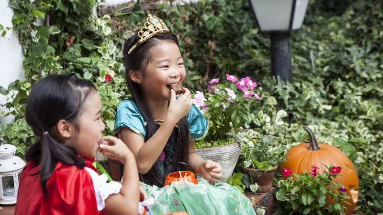 little girls in Halloween costumes eating chocolate