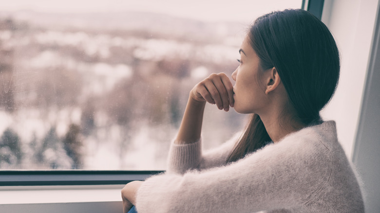 woman looking out window in winter 