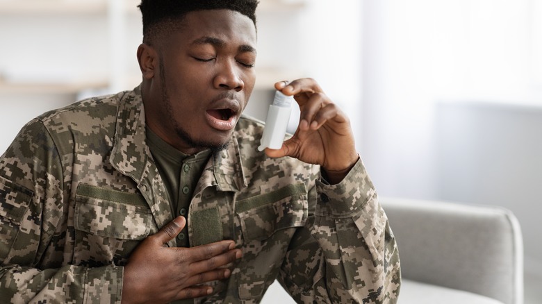 military man holding inhaler and chest