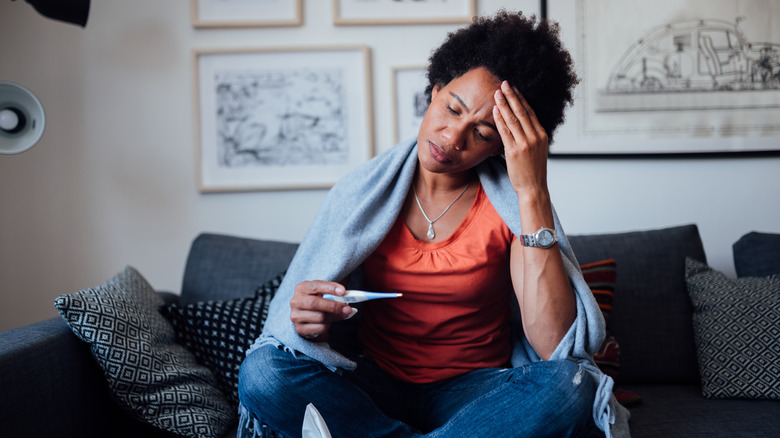 woman with headache checking for fever