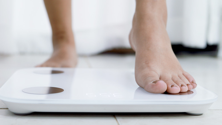 Woman's feet stepping on a scale