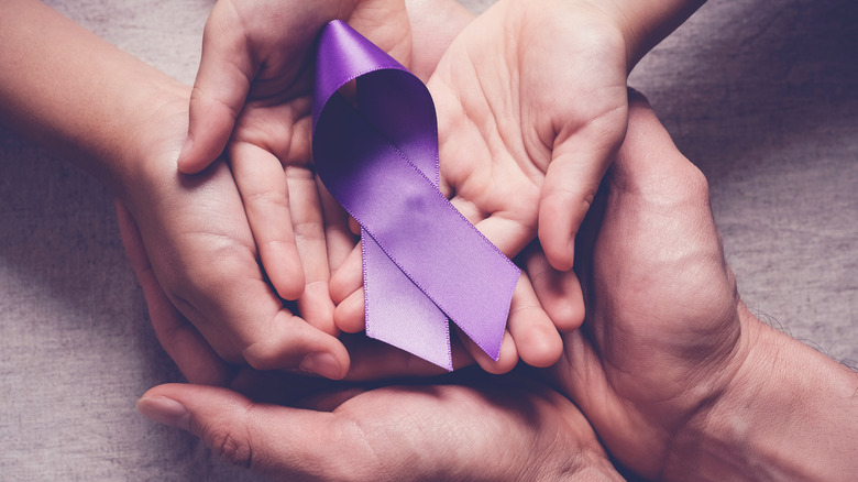 hands holding onto a purple ribbon