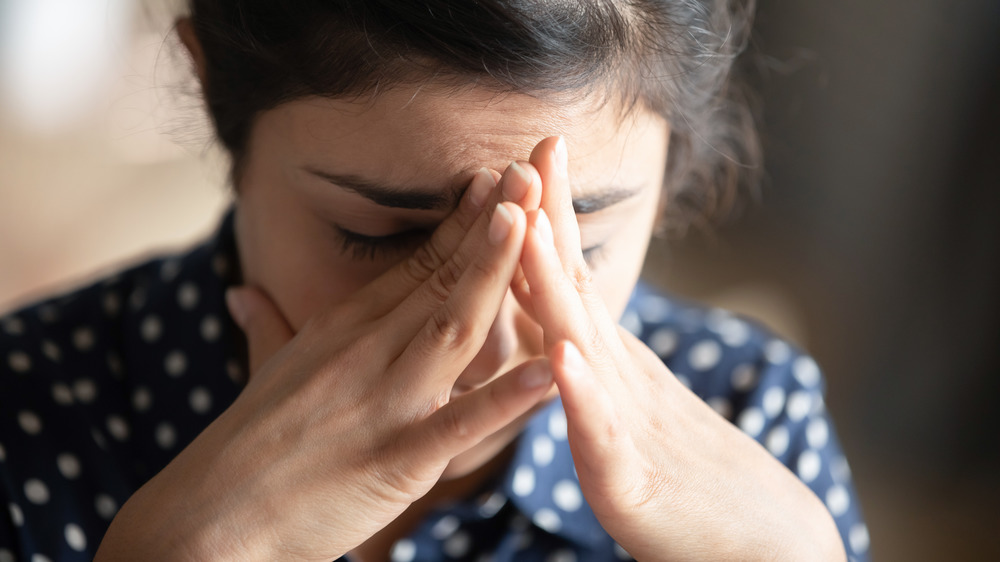 Closeup of a woman with her head on her hands in distress