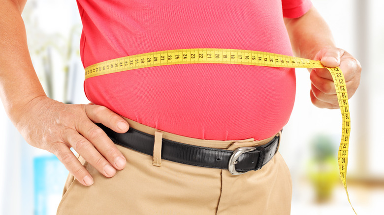 man measuring waistline