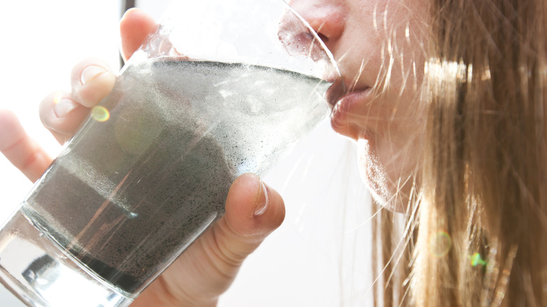 woman drinking dirty water from glass