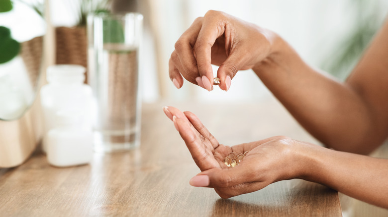 woman's hands holding fish oil supplements