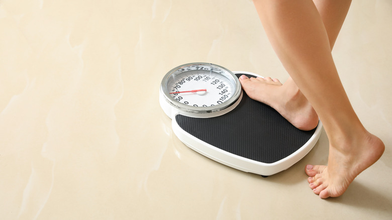 person stepping on weighing scale