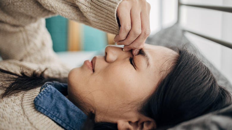 Woman laying in bed pinching brows